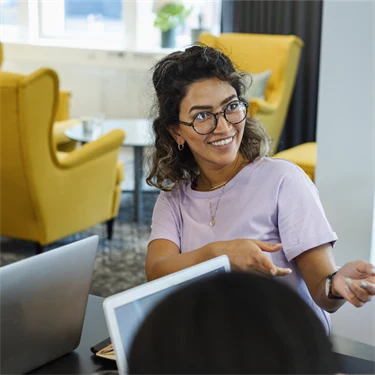 Glada kollegor samtalar vid bord med datorer.