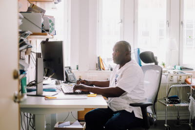 Vårdare sitter framför dator vid skrivbord