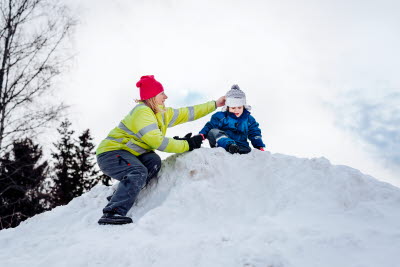Förskolepedagog och litet barn på en snökulle
