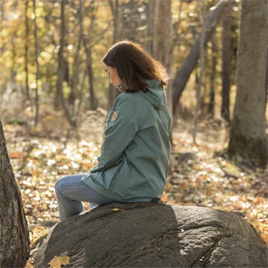 Kvinna sitter på sten i skogen
