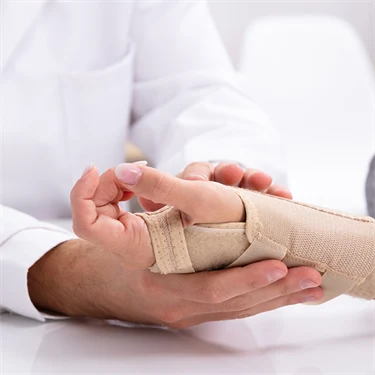 En kvinna får sin handled inlindad i bandage av en doktor.