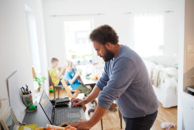 Hemmajobb vid dator med barn i bakgrunden