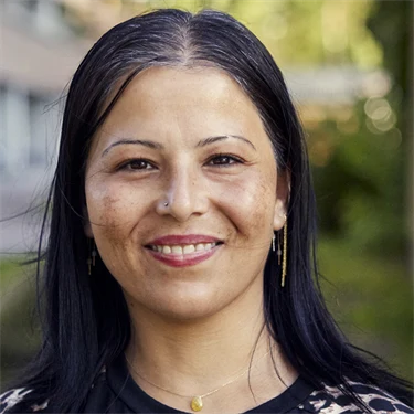 Ghada Almassri utomhus. Hon står mellan två höghus.
