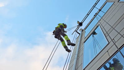 Byggnadsarbetare hänger utanför fasad