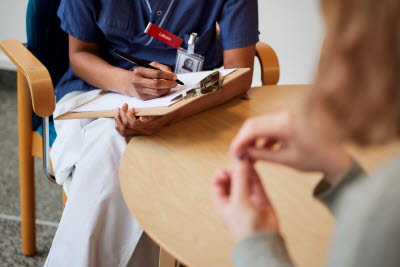 Sjukvårdare pratar med patient och skriver anteckningar