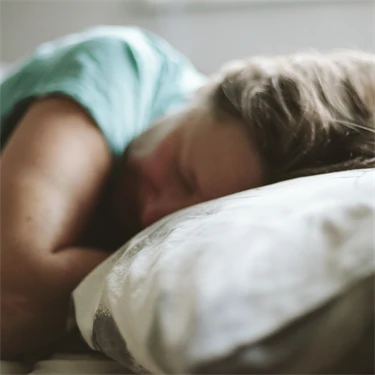 Kvinna som sover med huvudet på en kudde