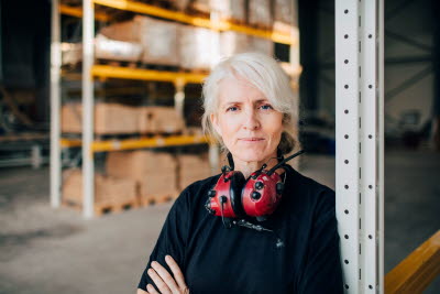 Kvinna på lager med hörselskydd runt nacken