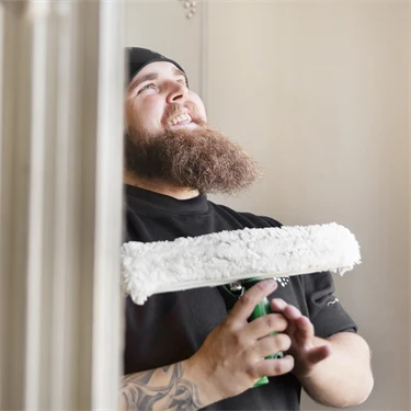 Målare med roller tittar upp mot taket