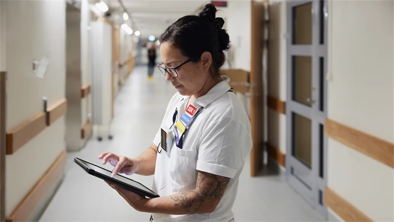 Akutmottagning på sjukhus med vårdpersonal som står i en korridor med en surfplatta