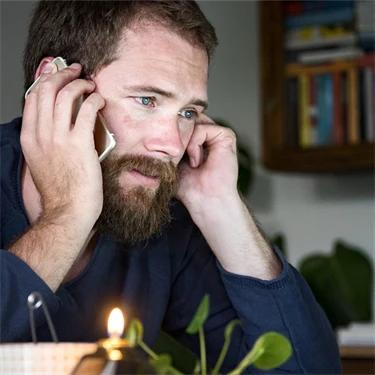 Man vid dator som pratar i telefon