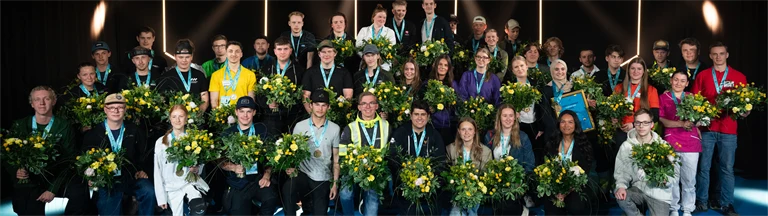 Gruppbild av alla guldmedaljörer i Yrkes-SM 2026, med medalj runt halsen och blombukett i handen.