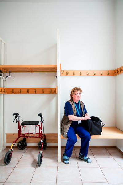 Kvinnlig vårdare i omklädningsrum, med rollator