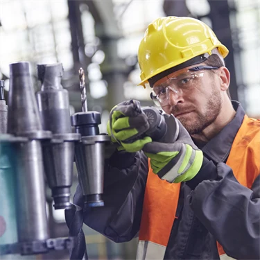 Man i skyddskläder undersöker något i fabrik eller verkstad