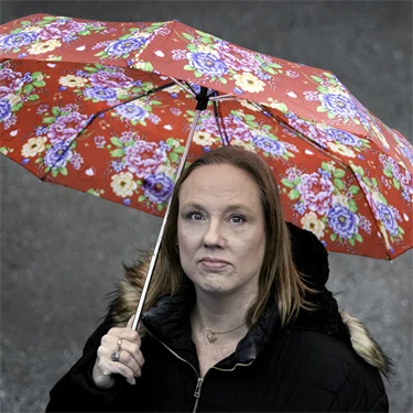Person som står ute under ett paraply.