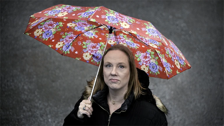 Person som står ute under ett paraply.