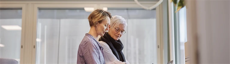 två personer sår vid ett skrivbord och jobbar med dator