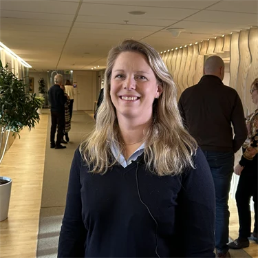 Emelie Thern, forskare, står i Afa Försäkrings korridor och ser glad ut.