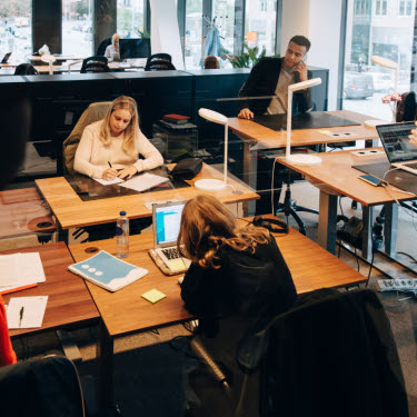 Medarbetare arbetar koncentrerat runt skrivbord på kontor